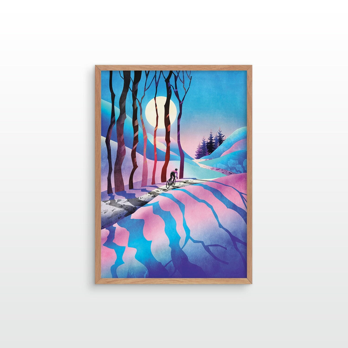 Art print depicting a stylized winter landscape with pink and blue hills, dark tree silhouettes, a pale moon, and a small figure on a path, shown against a light gray wall.