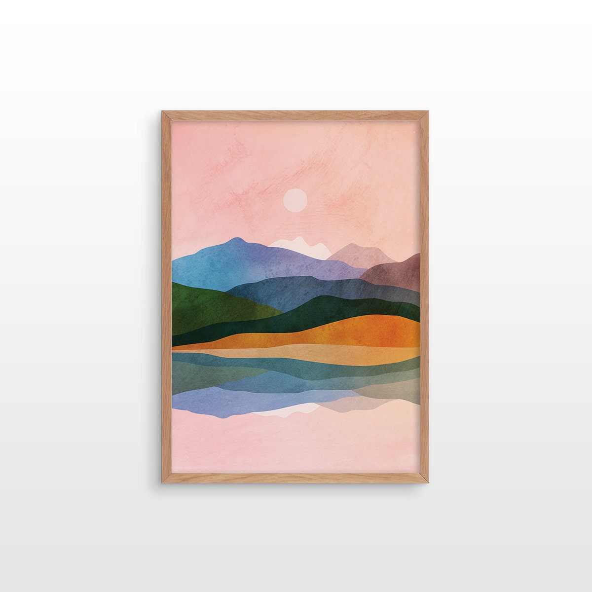 A framed minimalist landscape art print featuring stylized mountains, hills, and water in pastel pink, blue, green, and orange tones, set against a clean white background.
