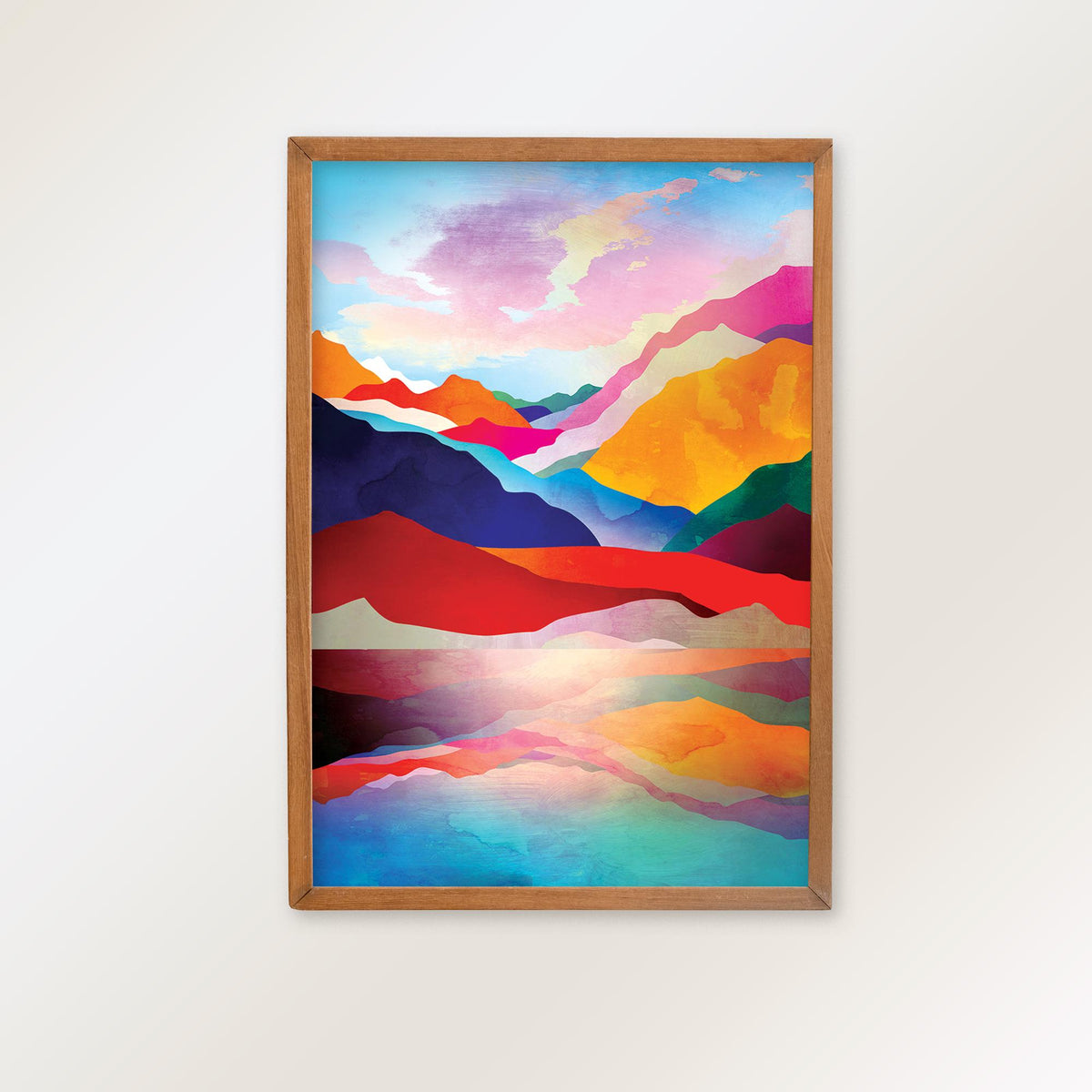 A framed abstract landscape art print featuring vibrant, colorful mountain peaks and a reflective lake, enclosed in a light brown wooden frame and mounted on a plain white wall.