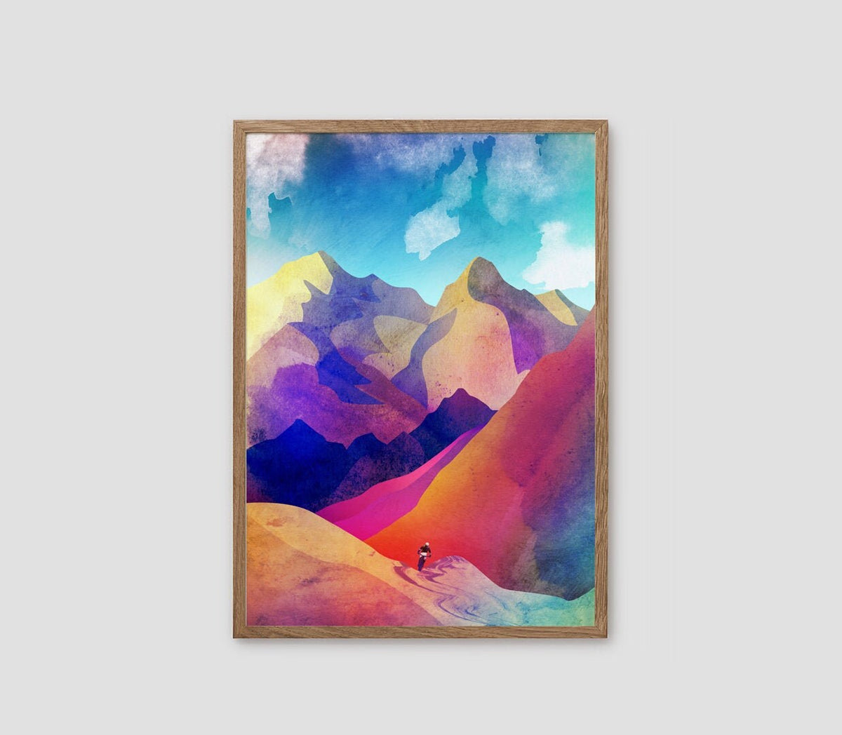 A framed art print featuring a colorful, watercolor-style mountain landscape with a small hiker, displayed against a light gray background.