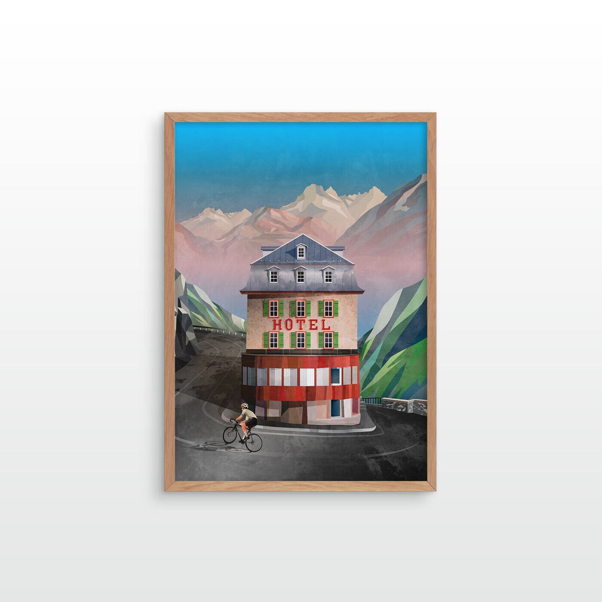 A framed art print depicting a vintage mountain hotel with a cyclist in front, set against stylized green mountains and a blue sky, displayed on a light gray wall.