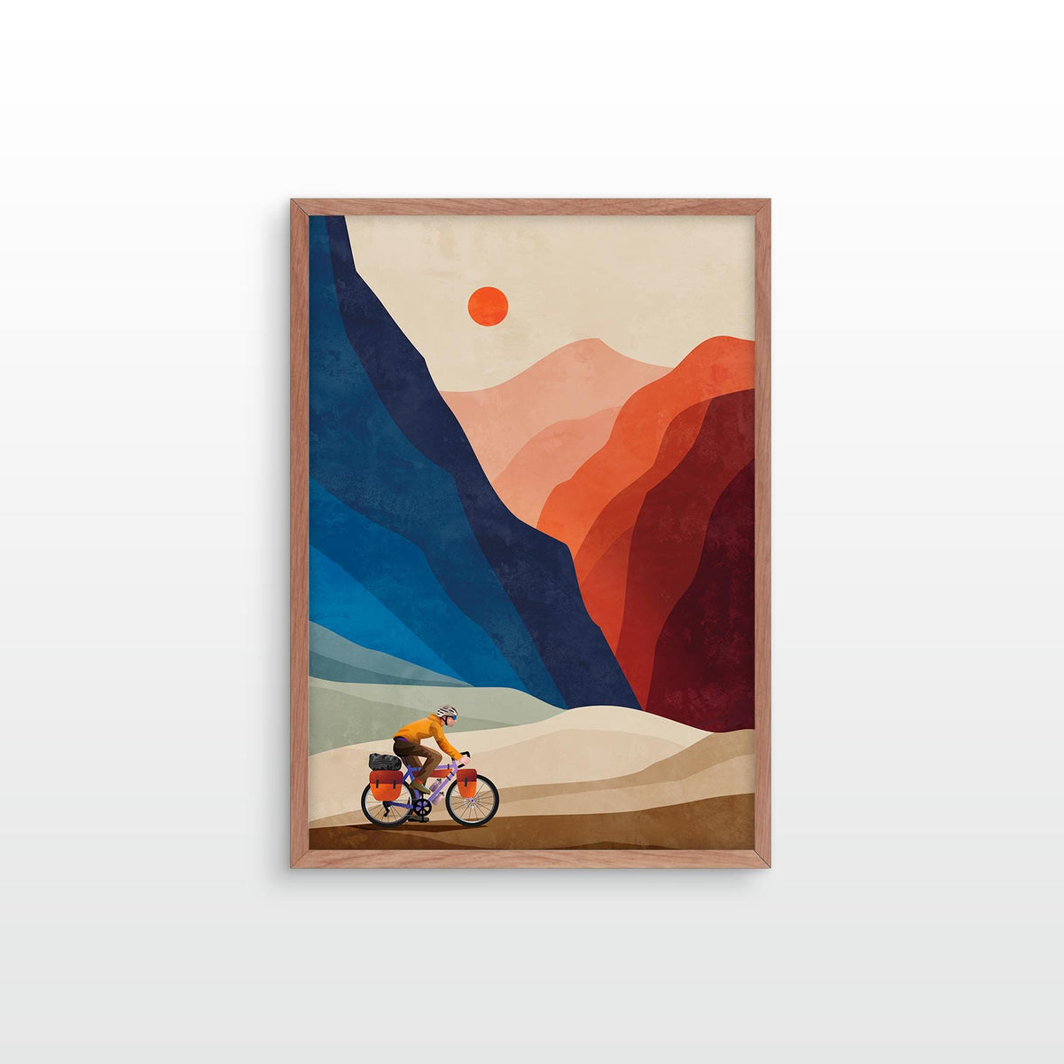A framed art print featuring a stylized illustration of a cyclist riding through a mountainous landscape under a red sun, displayed on a clean white wall.