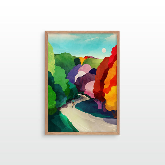 A framed art print featuring a colorful, abstract landscape painting with green hills, a winding pale path, and bold red, orange, yellow, purple, and blue shapes under a light blue sky, displayed against a plain white wall.