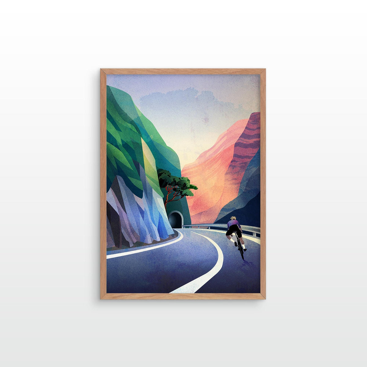 A framed art print featuring a stylized illustration of a cyclist on a winding mountain road, displayed on a clean white wall.