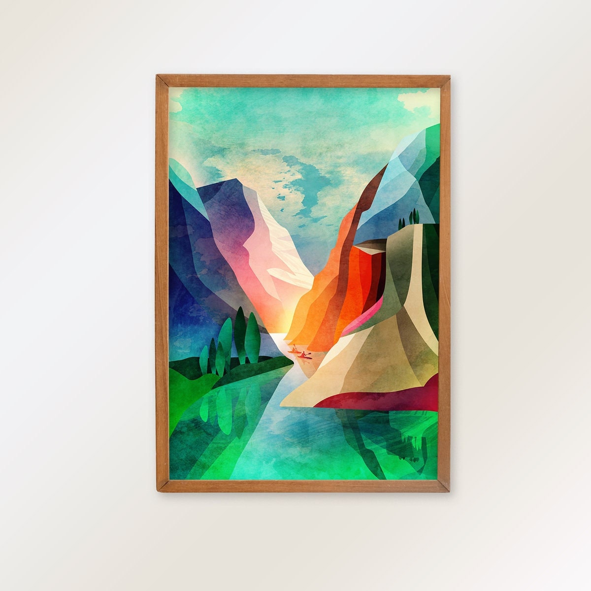A framed art print featuring a colorful geometric mountain landscape with green, blue, pink, orange, and beige shapes, displayed on a light neutral wall.
