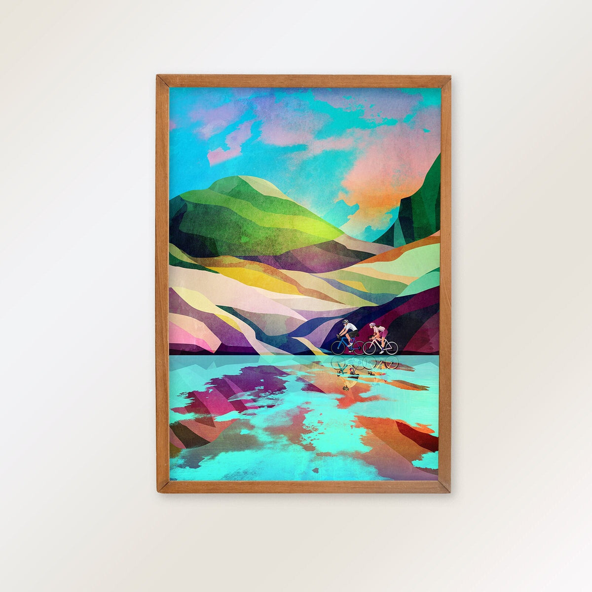 A framed art print featuring a colorful, geometric landscape with mountains, hills, and a reflective body of water, hung on a plain white wall.