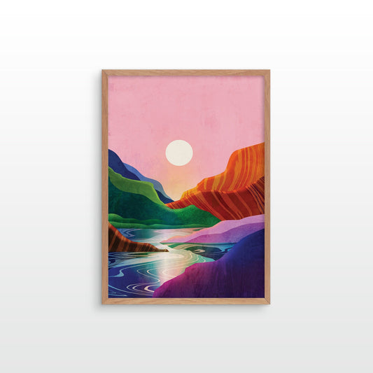 A framed art print featuring a colorful landscape with a pink sky, a white sun, green hills, and orange-red rock formations, displayed on a light gray wall.