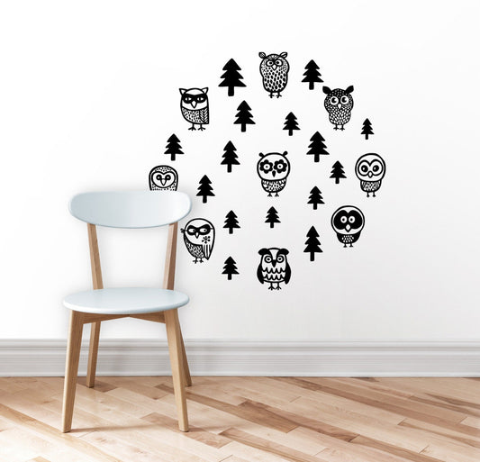 Black owl and tree wall decals arranged on a white wall above a light wood floor.