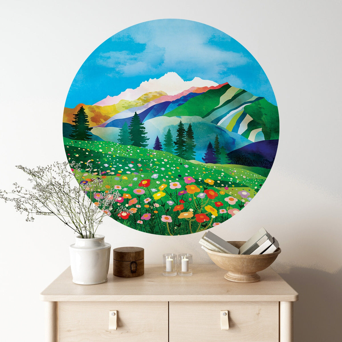 A large circular wall art print depicting a colorful mountain landscape with wildflowers