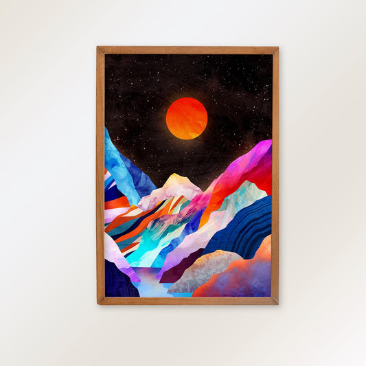A framed art print featuring a colorful, stylized mountain landscape under a starry black sky with a glowing orange sun, mounted on a light beige wall.
