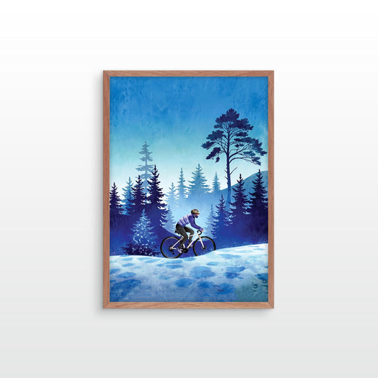 A framed art print depicting a cyclist riding through a snowy forest at night under a deep blue sky, mounted on a light gray wall.