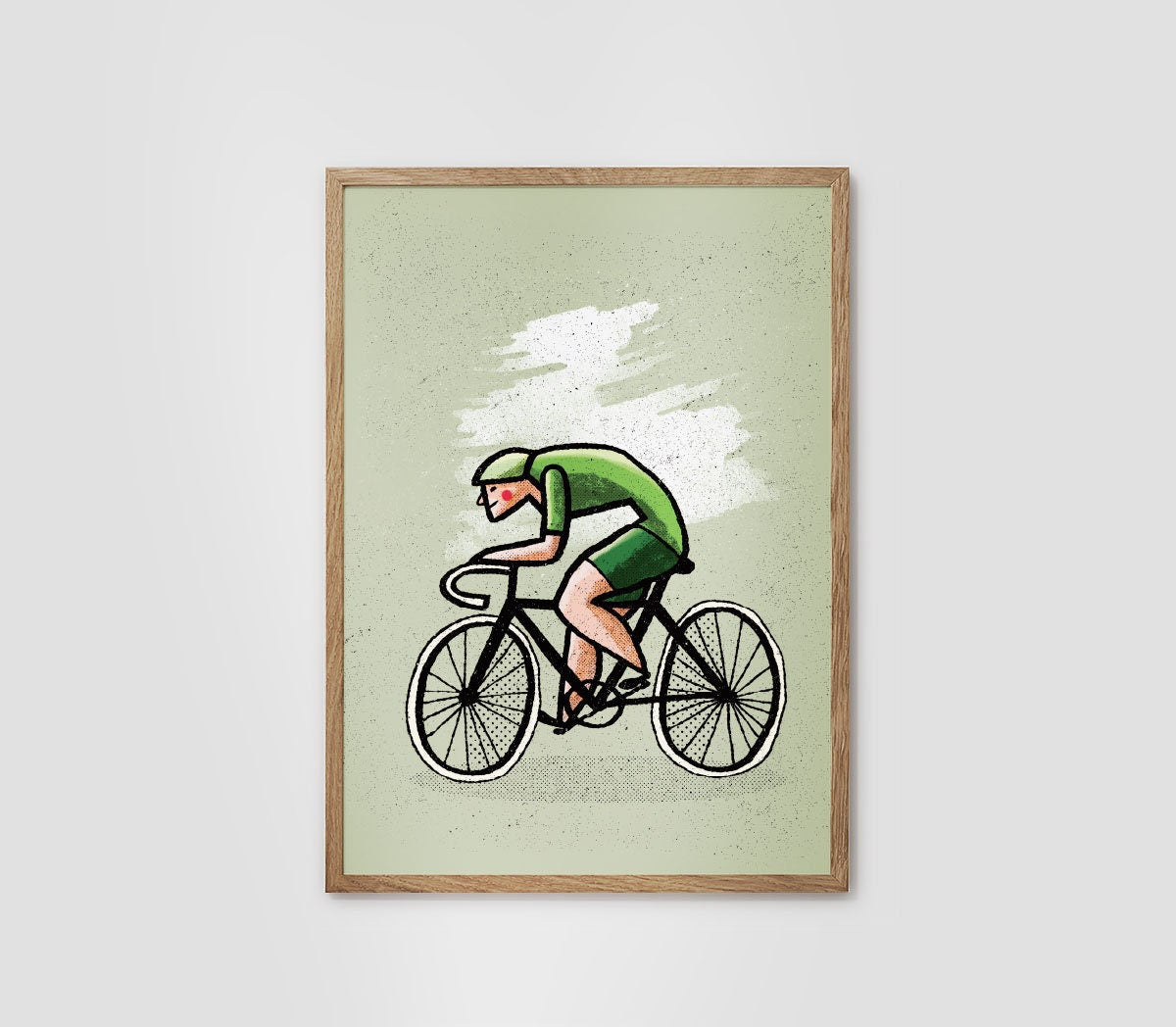 A framed art print featuring a minimalist illustration of a cyclist in a green jersey and shorts against a pale green background, displayed on a light gray wall.
