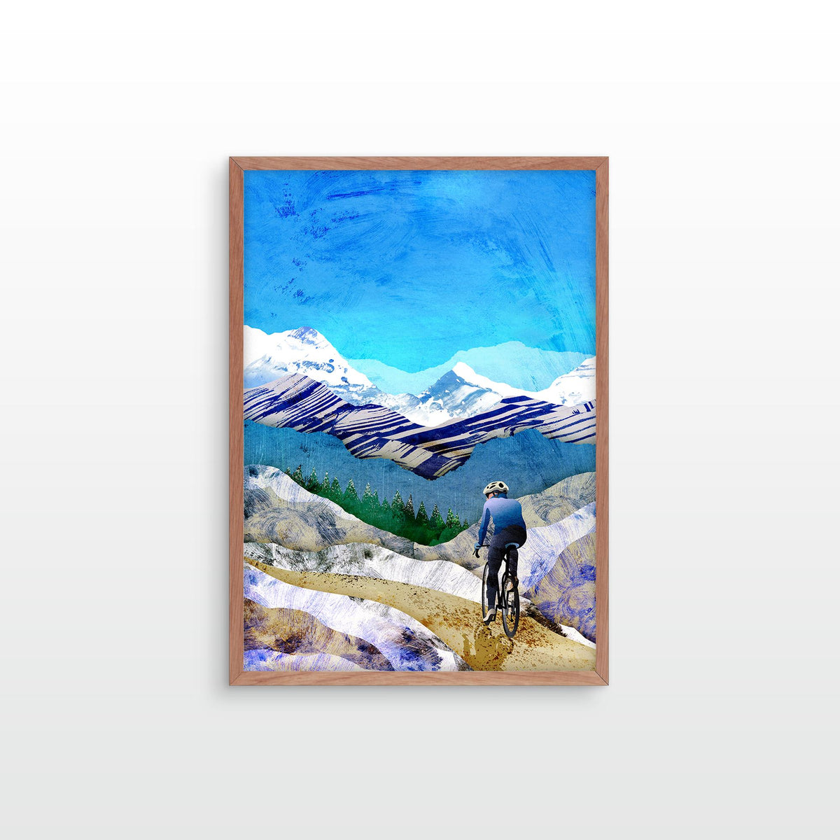 A framed art print depicting a cyclist from behind looking out over a mountain landscape with snow-capped peaks under a bright blue sky, mounted on a light gray wall.