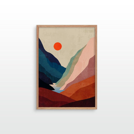 A framed minimalist landscape art print featuring geometric mountains and a sun in warm earthy tones, displayed against a clean white wall.