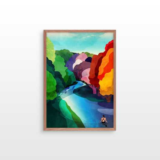 A framed art print featuring a colorful, abstract landscape painting with a winding blue river, green hills, and bright red, orange, and yellow rock formations, displayed on a light gray wall.