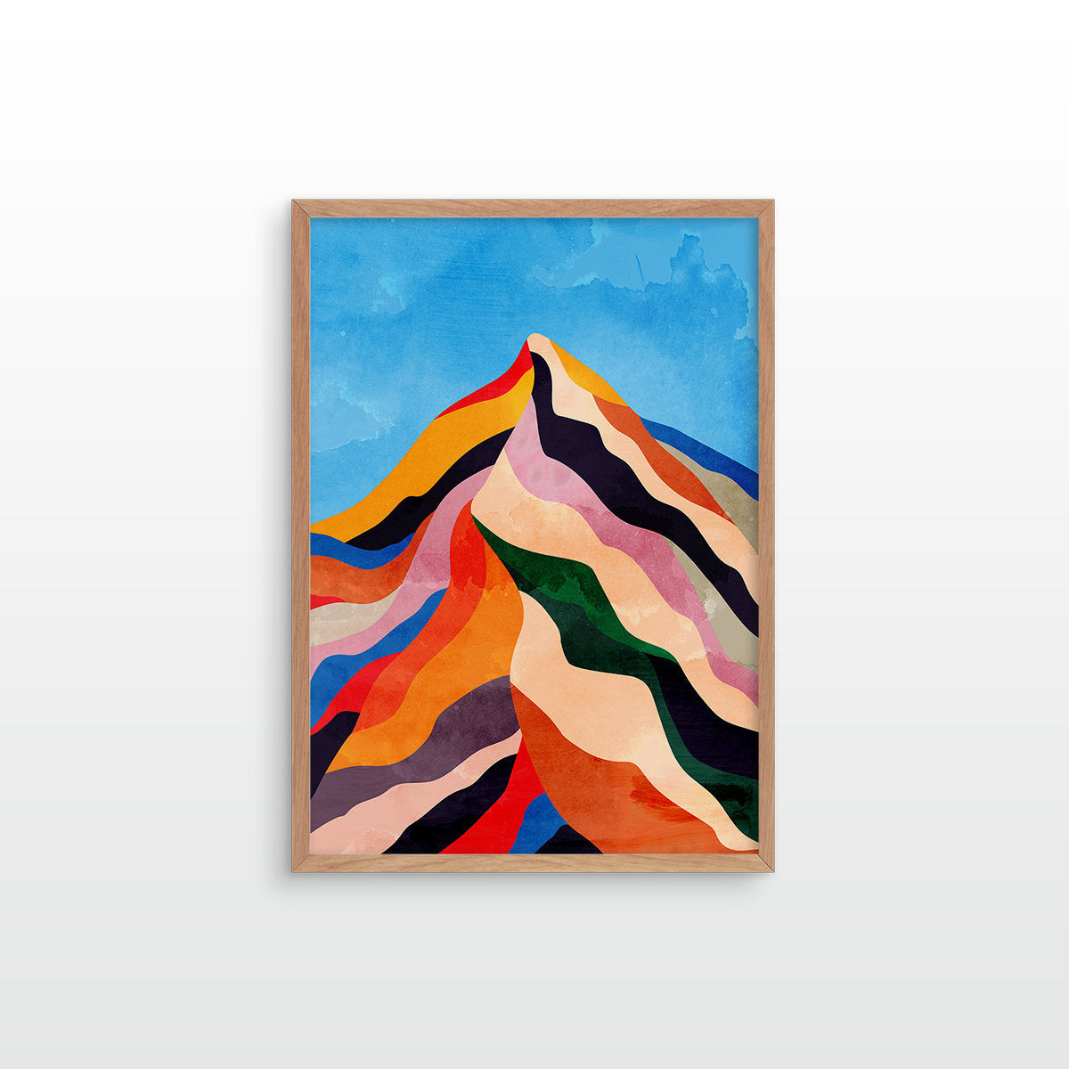 A framed abstract art print depicting a colorful mountain peak with wavy, layered stripes in blue, orange, red, green, pink, beige, and black, set in a light wood frame against a white wall.