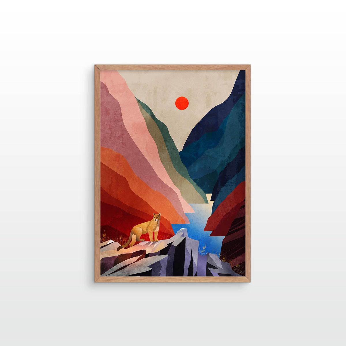 A framed art print featuring a stylized mountain landscape with layered red, pink, blue, and green shapes, a small yellow figure near the bottom, and a red sun in the sky, shown against a light gray wall.