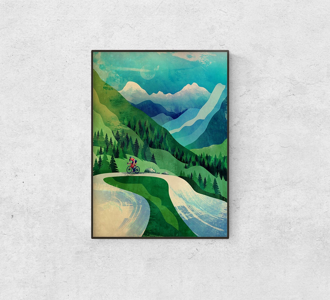 A framed art print depicting a scenic mountain landscape with a cyclist on a winding road