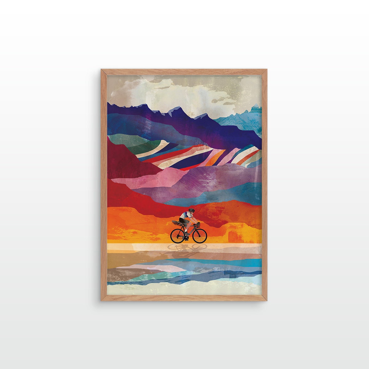 A framed art print featuring an abstract landscape with a cyclist riding along a reflective shoreline, set against a clean white background.